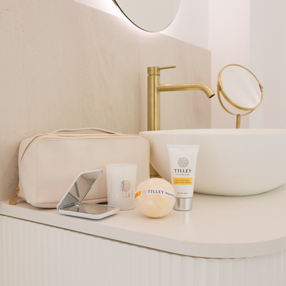 Their Little Escape gift set - Tilley skincare products, gold cosmetics pouch, compact mirror and bath bomb on a bathroom counter
