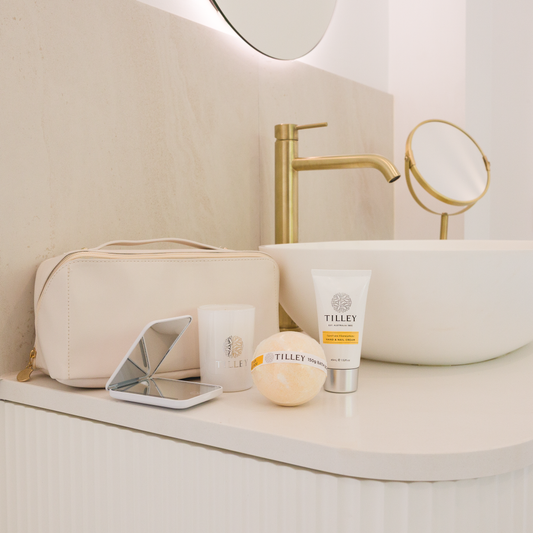 Their Little Escape gift set - Tilley skincare products, gold cosmetics pouch, compact mirror and bath bomb on a bathroom counter