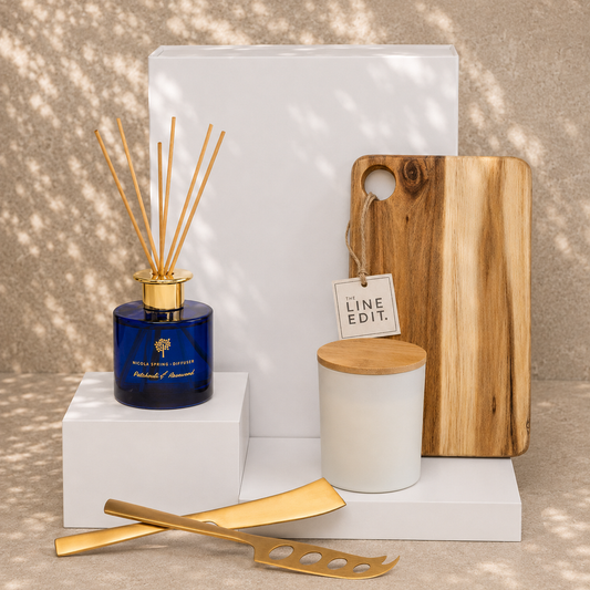 A Little Calm at Home luxury relaxation gift hamper — reed diffuser, soy candle, serving board and gold cheese knives in a white gift box by The Gifting Pantry