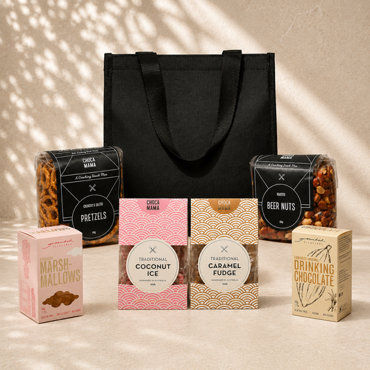 aA Little Hello sweet gift hamper flat lay – black tote bag with Chocamama pretzels, coconut ice, caramel fudge, beer nuts, Grounded Pleasure drinking chocolate and marshmallows