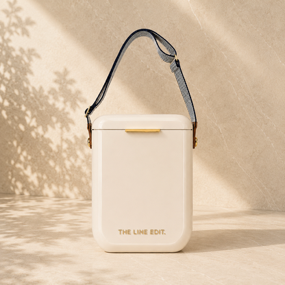 The Line Edit Pavilion cooler in cream, 10 litre hinged lid with a webbing shoulder strap and gold hardware