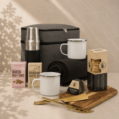 Escape for Two couples gift hamper flatlay — vacuum flask, enamel mugs, drinking chocolate, marshmallows, crackers, serving board and fleece throw
