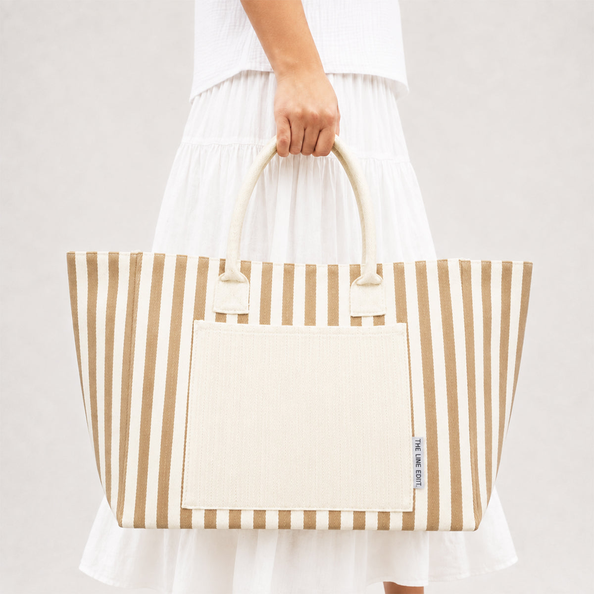Hampton tote in Natural by The Line Edit, a structured striped canvas bag carried by hand