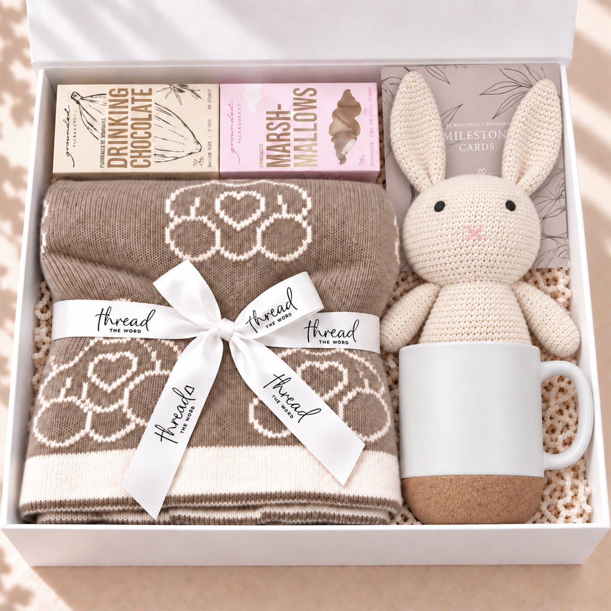 The Cosy Welcome baby gift hamper in Eggshell, teddy bear blanket, bunny, mug, drinking chocolate and marshmallows in a white gift box