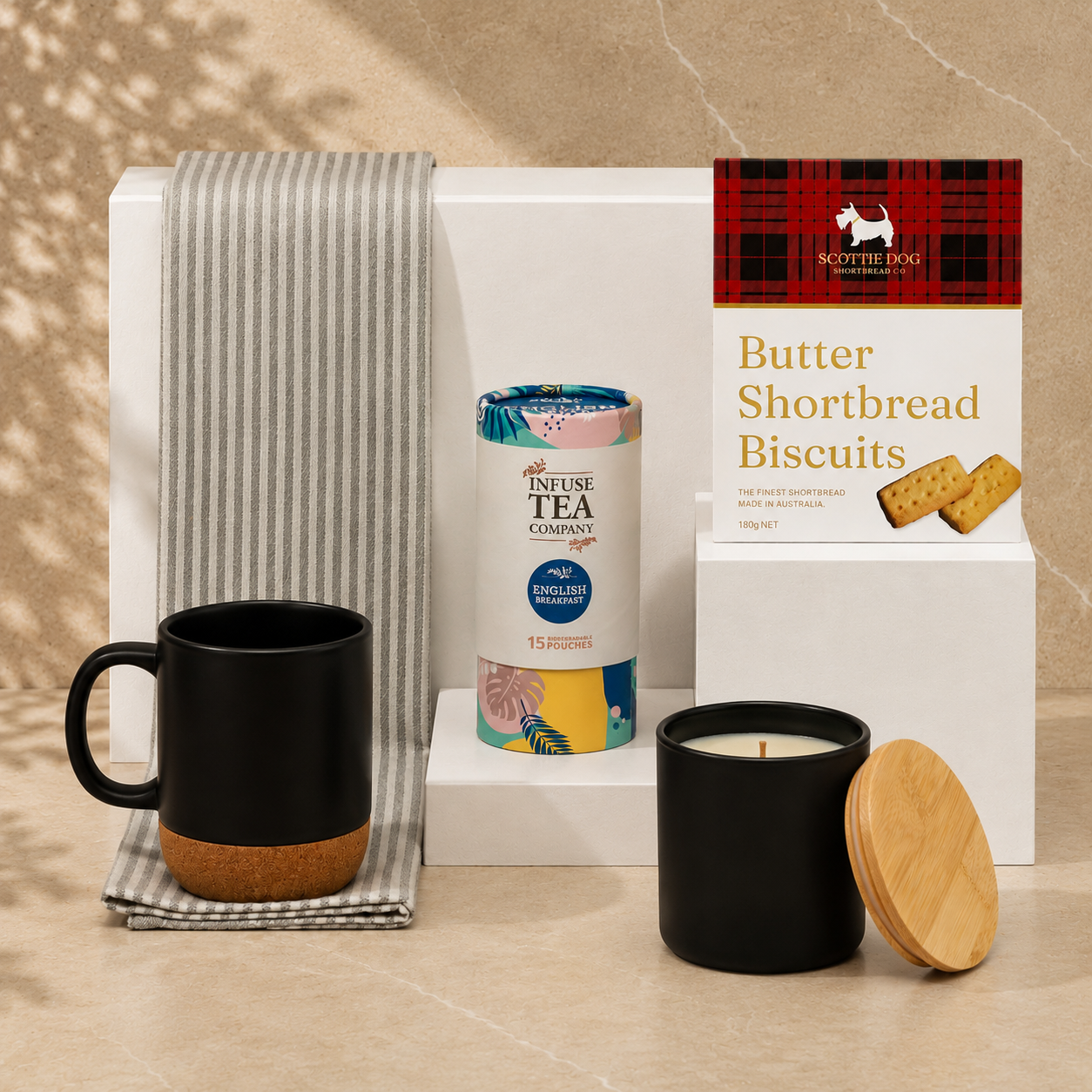 Make Yourself at Home black gift box - flat lay showing black ceramic mug, Infuse English Breakfast tea, Scottie Dog shortbread biscuits, black soy candle and striped tea towel