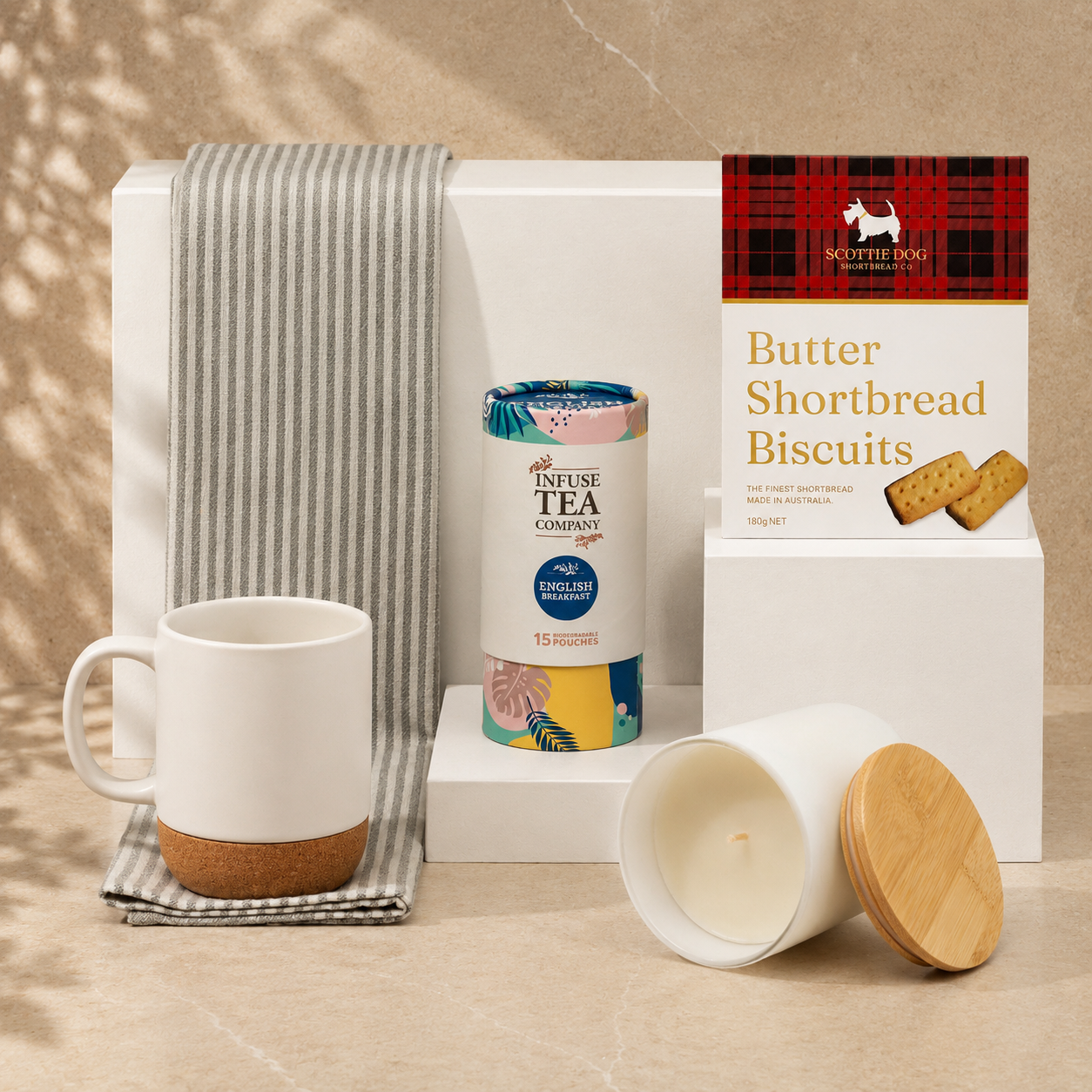 Make Yourself at Home white gift box - flat lay showing ceramic mug, Infuse English Breakfast tea, Scottie Dog shortbread biscuits, vanilla soy candle and striped tea towel
