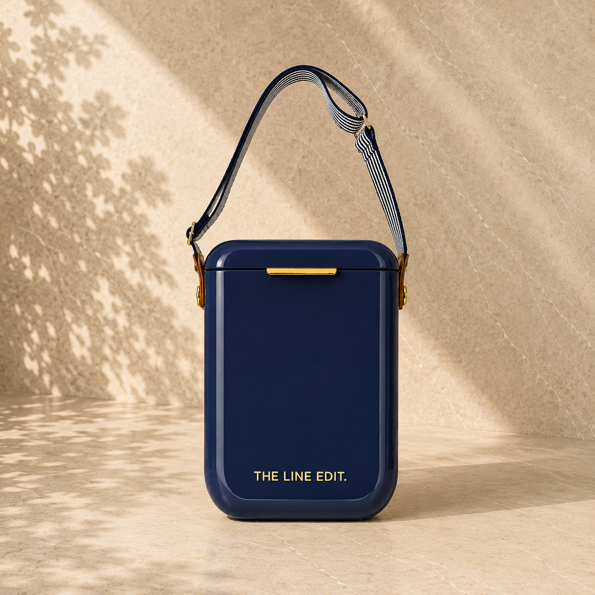 The Line Edit Pavilion cooler in navy blue, 10 litre hinged lid with a webbing shoulder strap and gold hardware