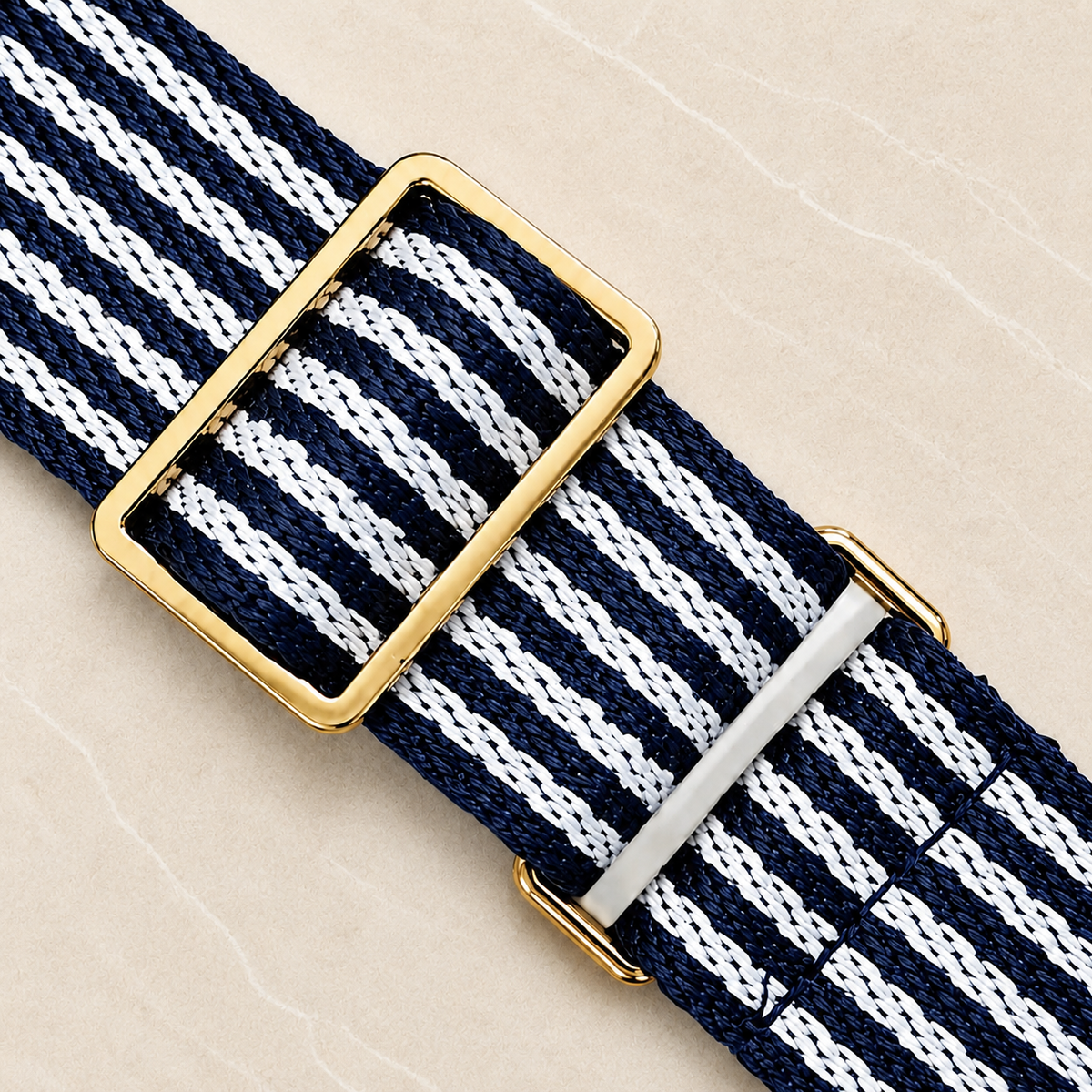 Close-up of the Pavilion cooler's navy and white striped webbing strap with a gold buckle