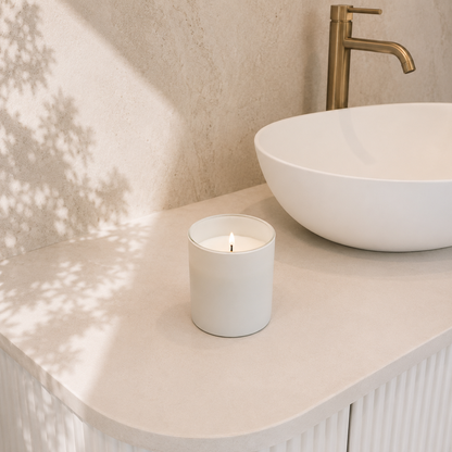 Vanilla scented white soy candle on bathroom counter with brass faucet - luxury self-care gift for Rest Recharge Repeat gift box