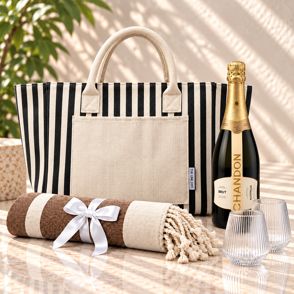 Sun and Sparkling gift hamper with a black striped Hampton tote, Chandon sparkling, two fluted Velora tumblers and a Turkish towel tied with ribbon