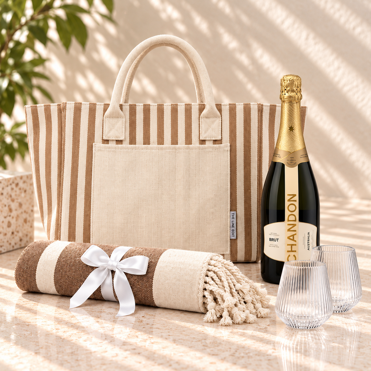 Sun and Sparkling gift hamper with a natural striped Hampton tote, Chandon sparkling, two fluted Velora tumblers and a Turkish towel tied with ribbon