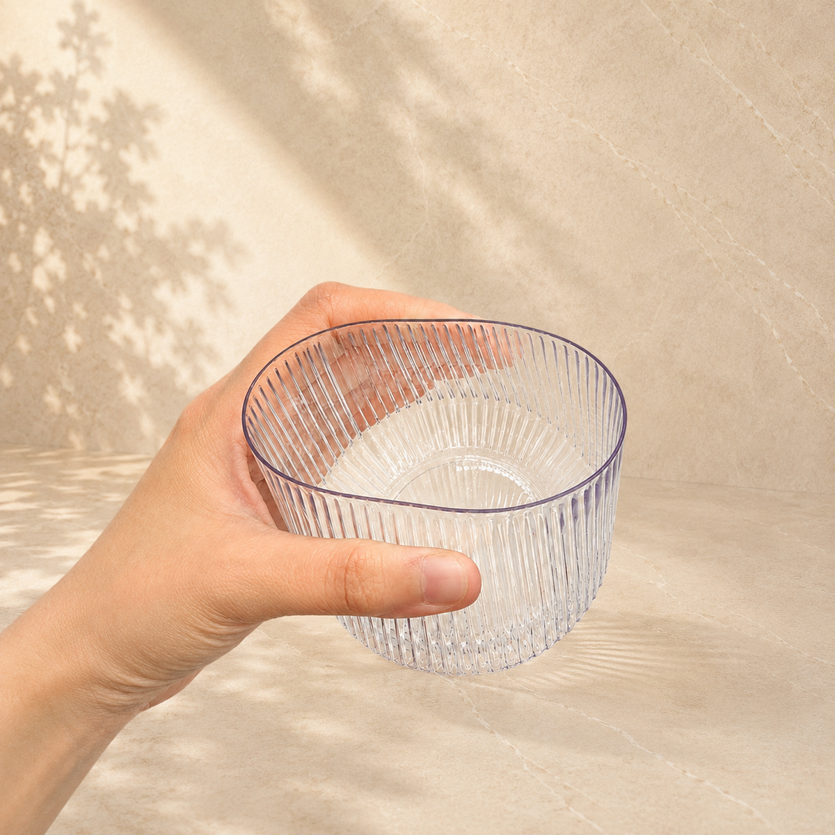 A hand holding a Velora fluted tumbler, showing its clear glass look finish