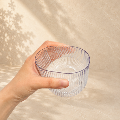 A hand holding a Velora fluted tumbler, showing its clear glass look finish